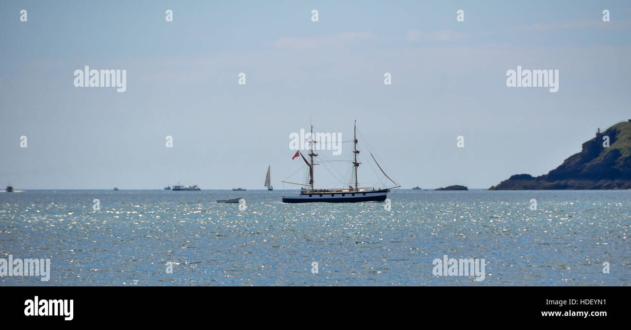 Unusual 'small' square rigger in the entrance to Milford Haven with other leisure boats on a calm sea on a summers day. Stock Photo