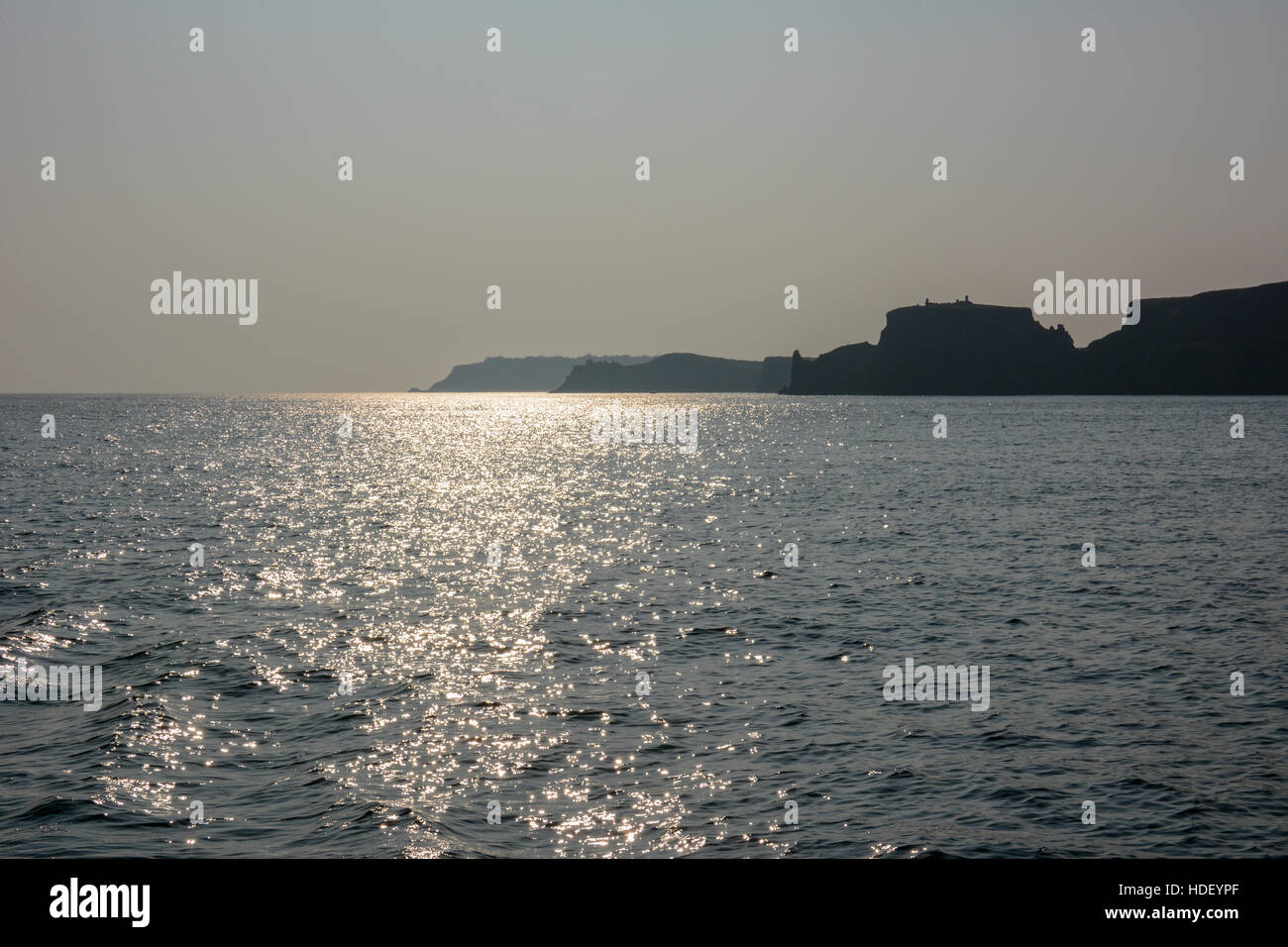 Three headlands in mist with reflection in a calm sea Stock Photo