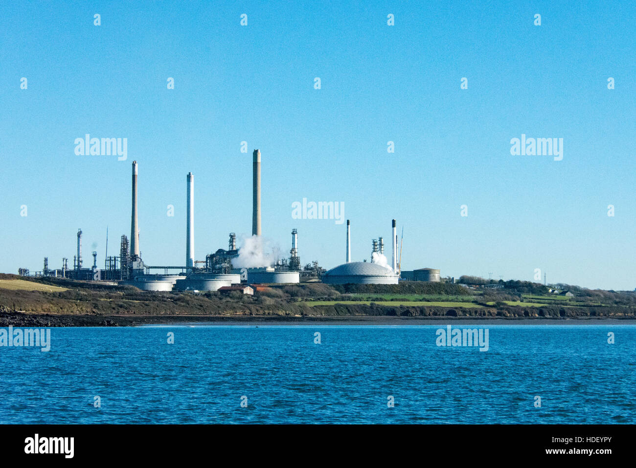 Pembroke refinery with a beautiful blue sky and calm blue sea in the foreground on a bright winters day. Stock Photo