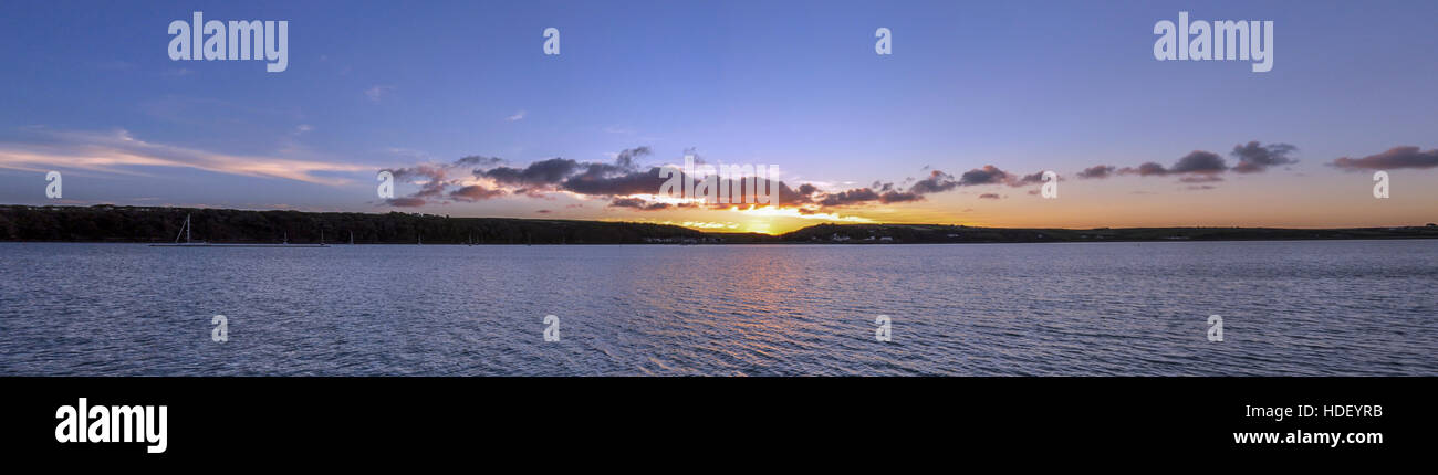High resolution panoramic Autumn sunset over Dale with clouds silhouetted against a blue and golden sky reflected in a calm sea Stock Photo