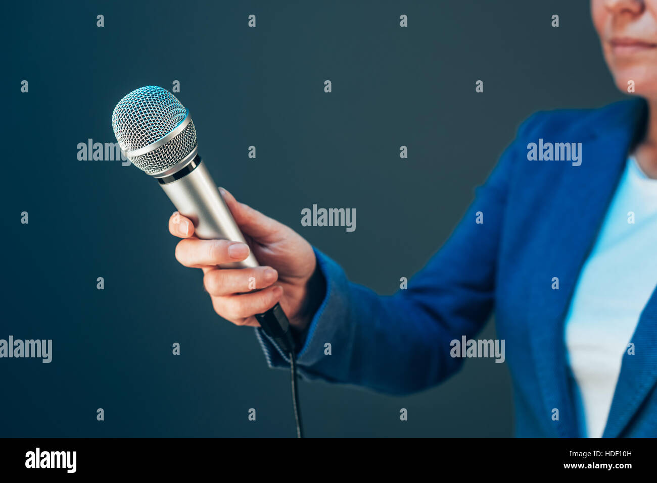 Elegant female journalist conducting business interview, hand with microphone Stock Photo