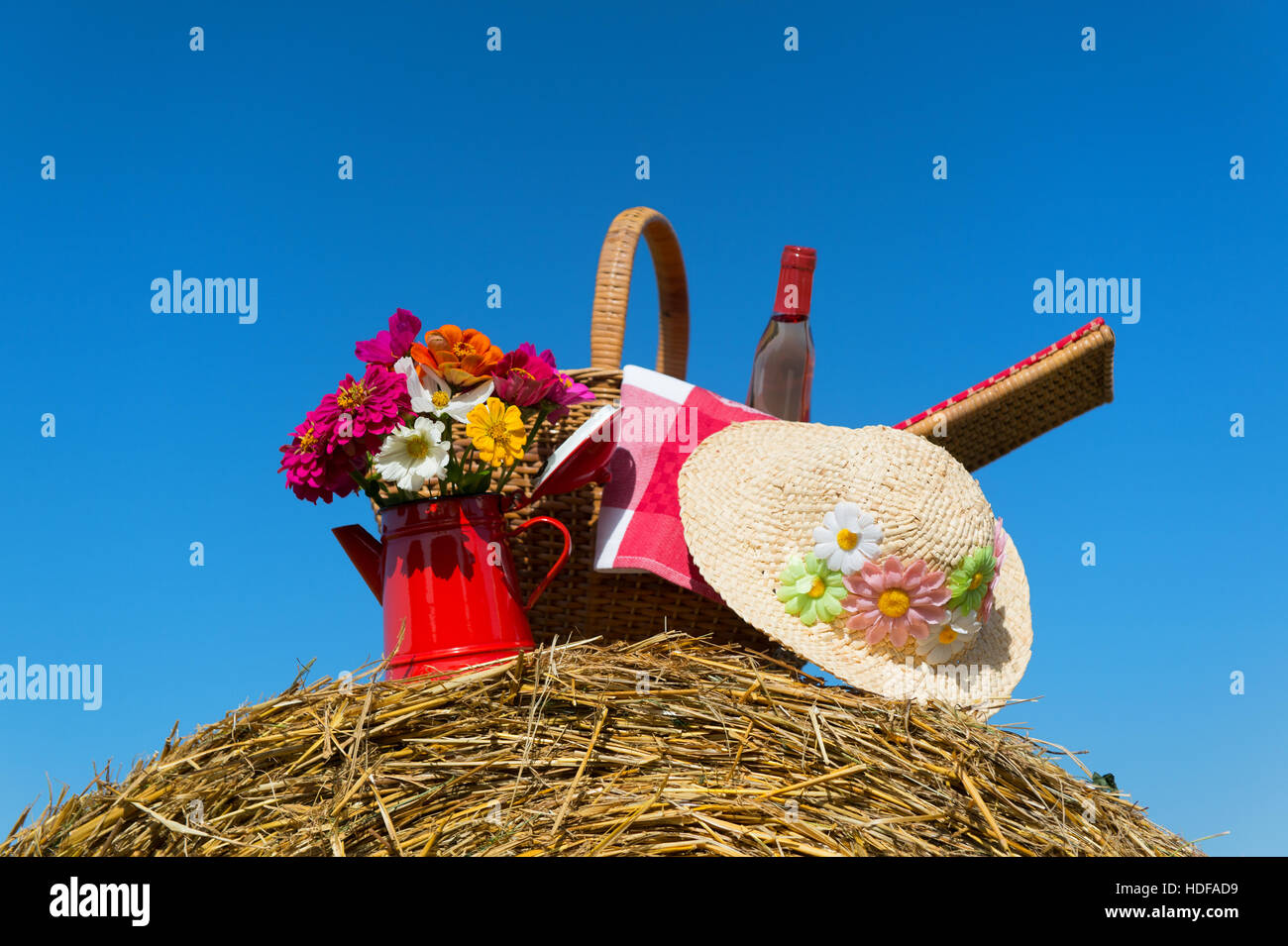 Bouquet garden flowers picnic basket and summer hat on hay roll in ...