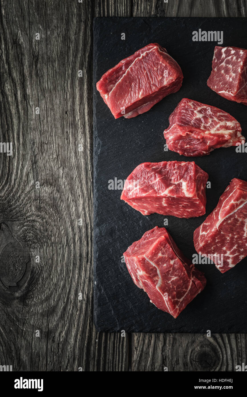 Raw angus beef slices on the black stone  on the wooden table vertical Stock Photo