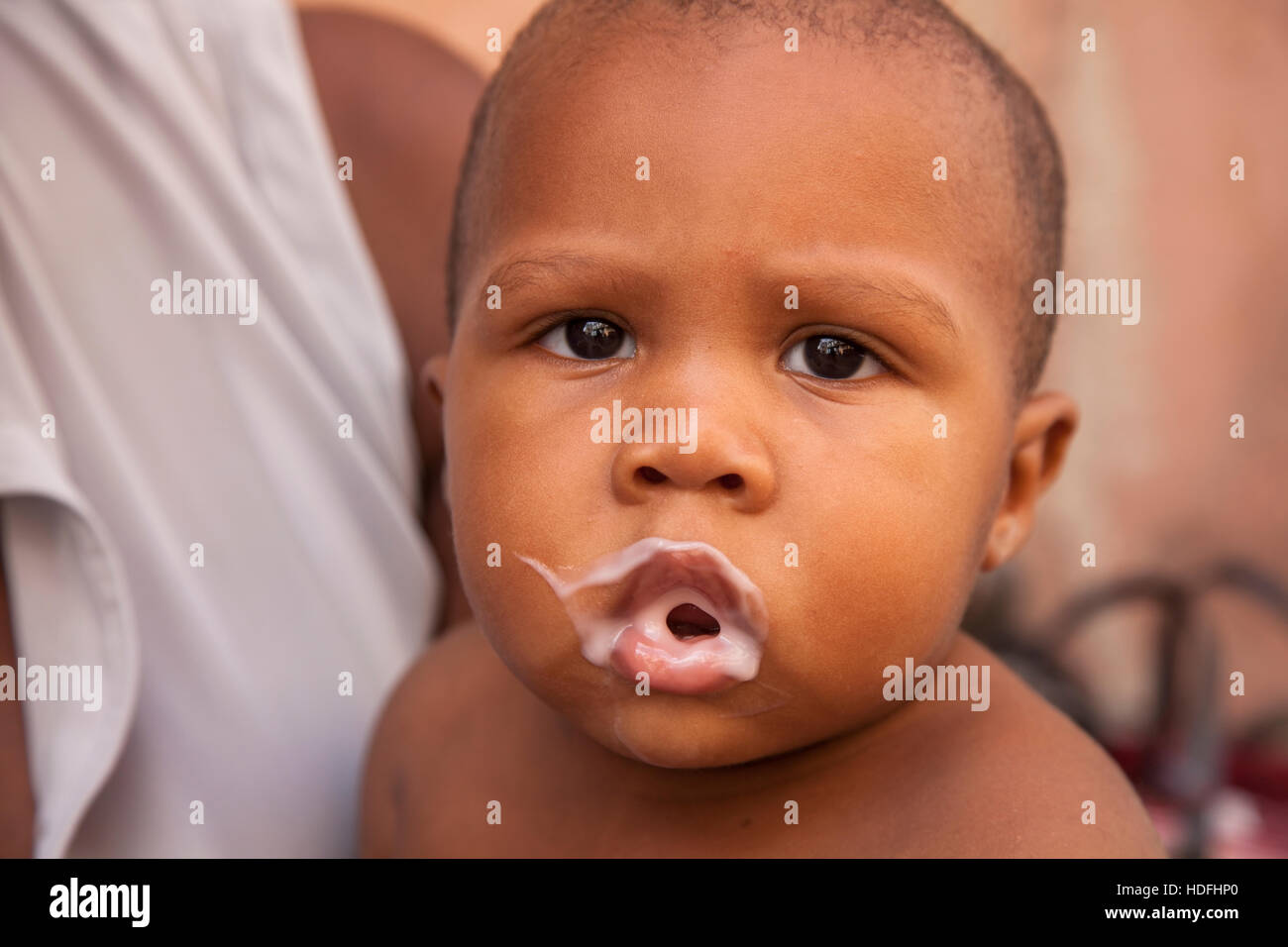 A baby with a messy face covered in yogurt after eating in Central Havana, Cuba. Stock Photo
