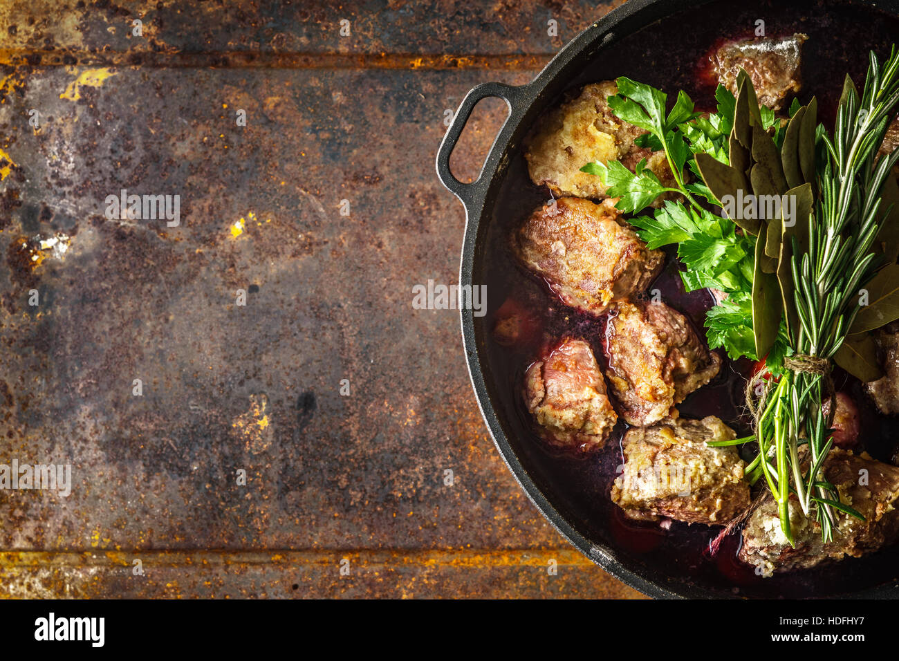 Boeuf Bourguignon with herbs in the pan on the metal background top view Stock Photo