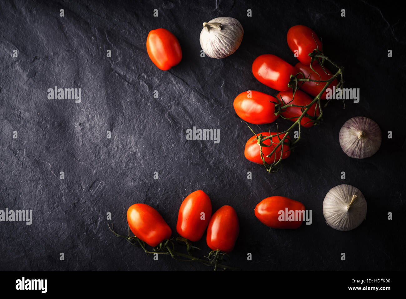 Cherry tomatoes with garlic on the black stone table Stock Photo - Alamy