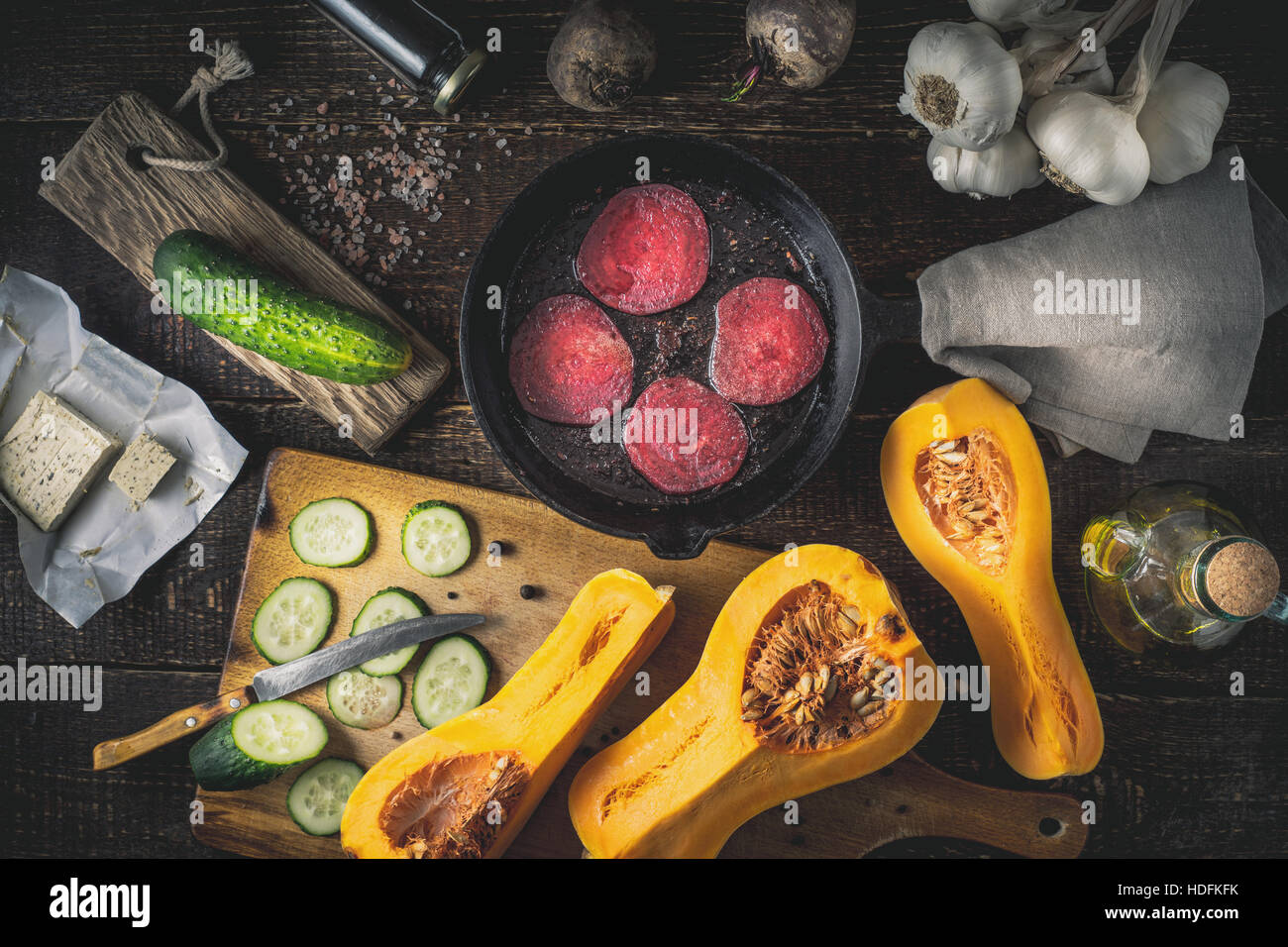 Sliced beet fried in the pan with different vegetables on the wooden