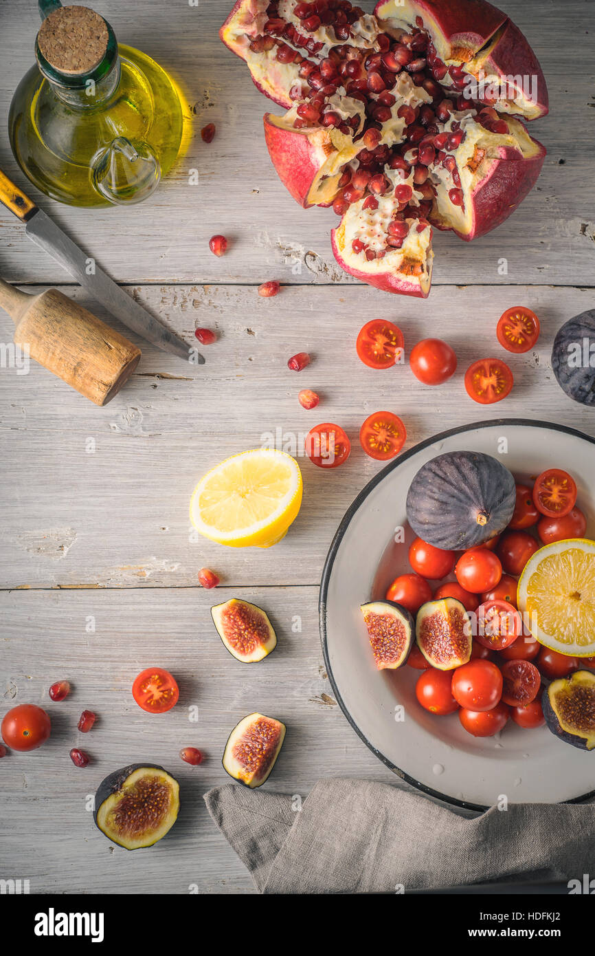 Pomegranate with figs and cherry tomatoes on the white wooden table vertical Stock Photo