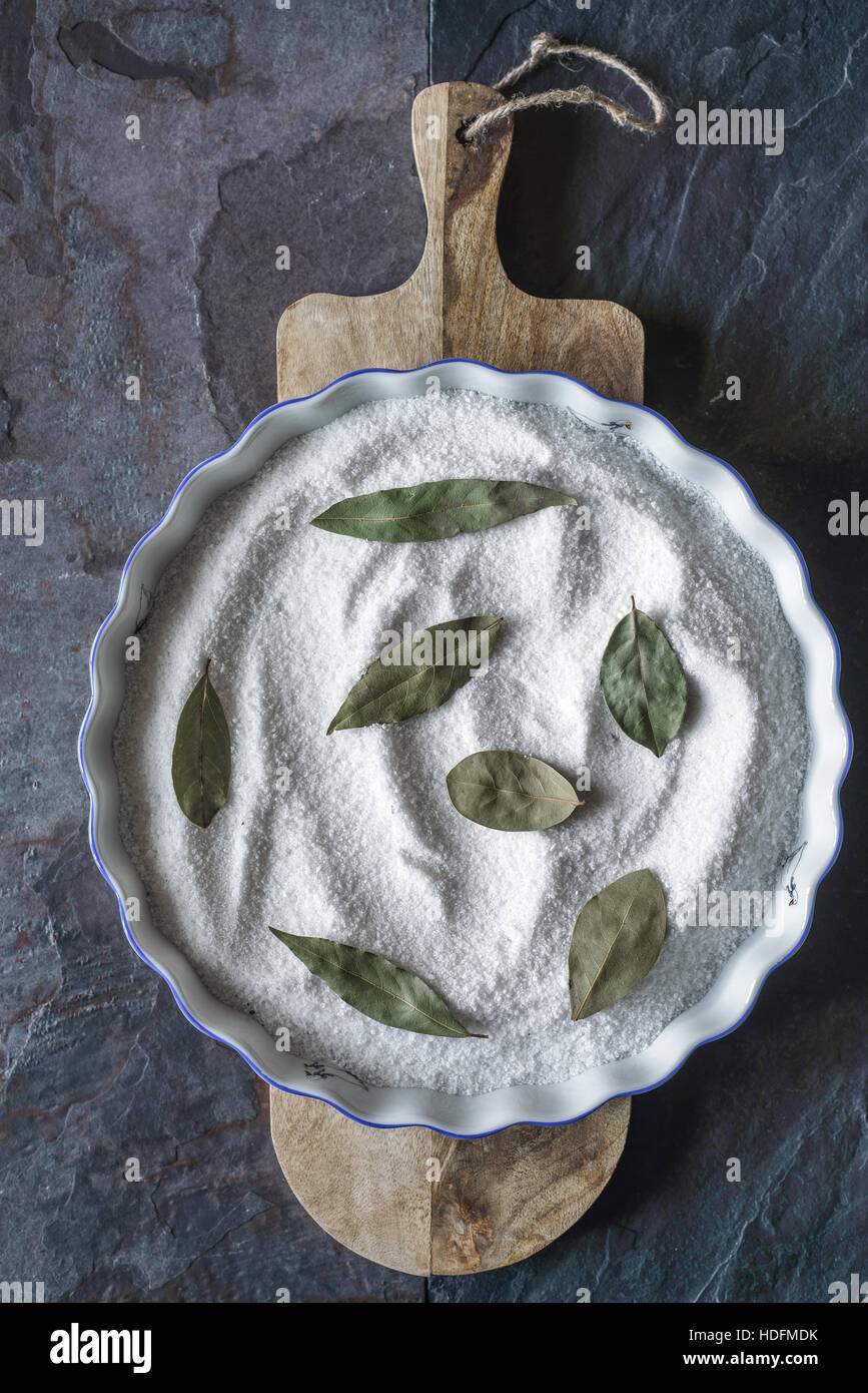 Baking dish with salt and bay leaf on the stone background vertical Stock Photo