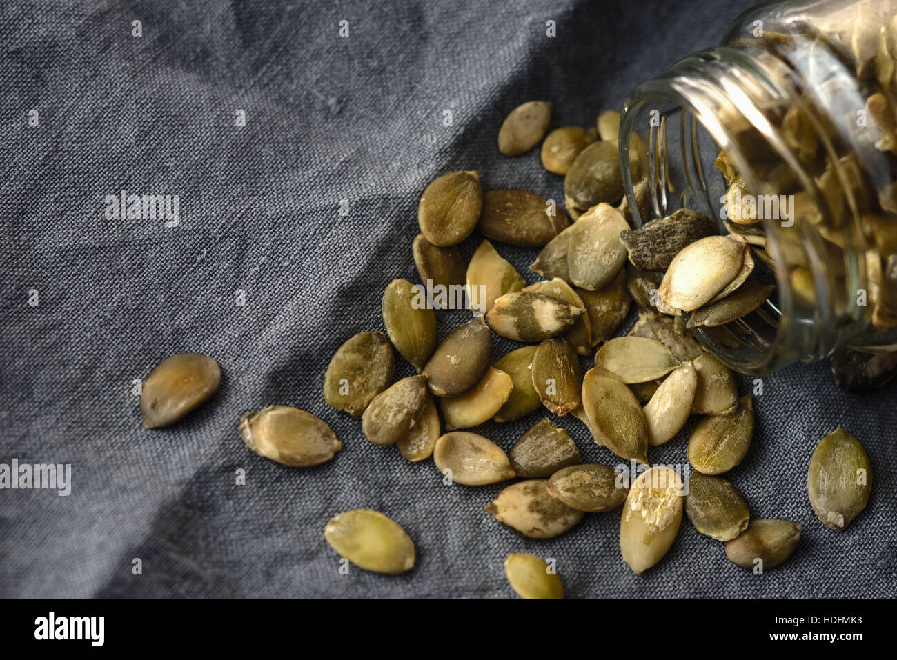 Pumpkin seeds in the glass jar  on the grey napkin Stock Photo