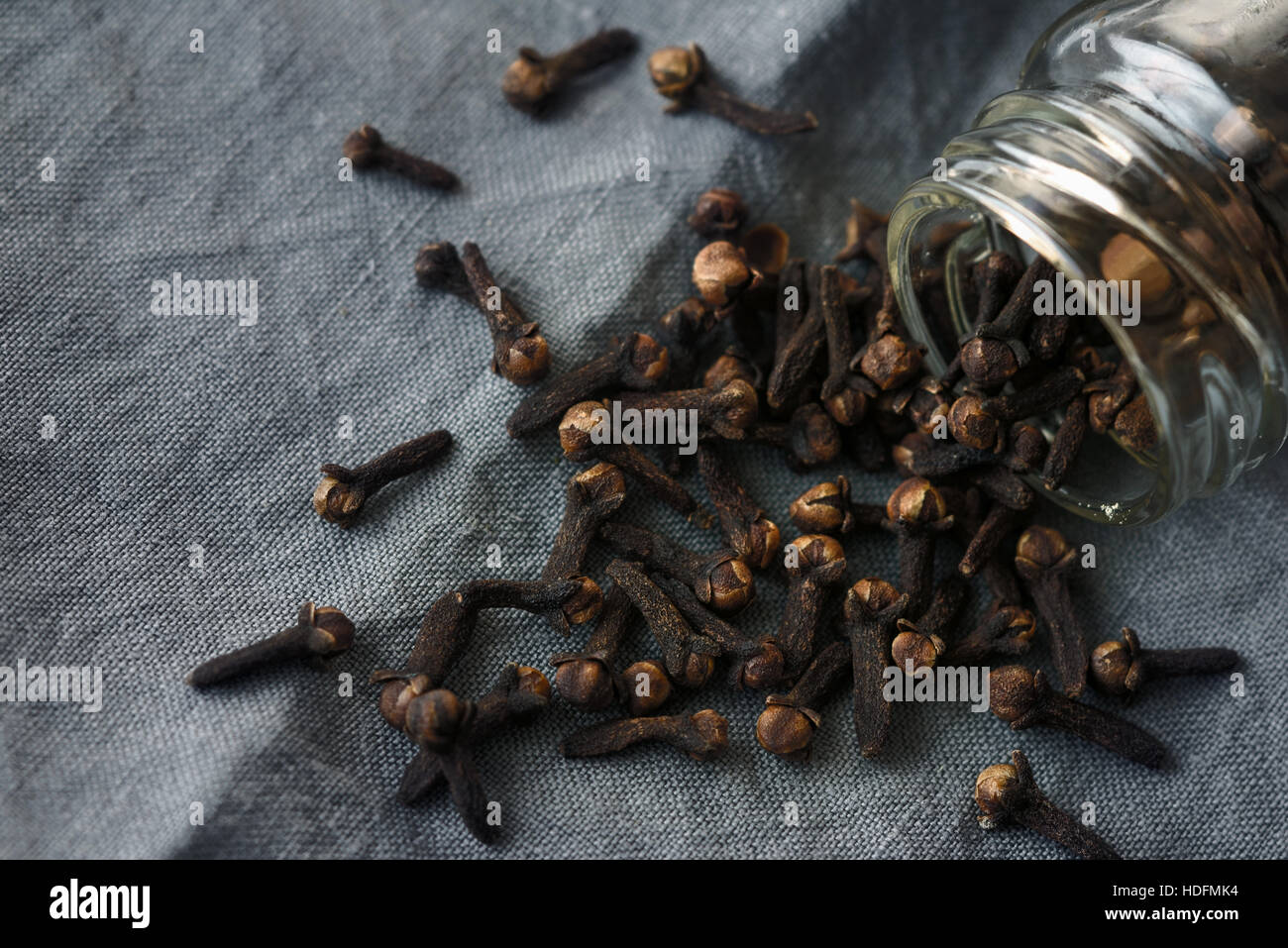 Cloves in the glass jar on the grey cloth Stock Photo