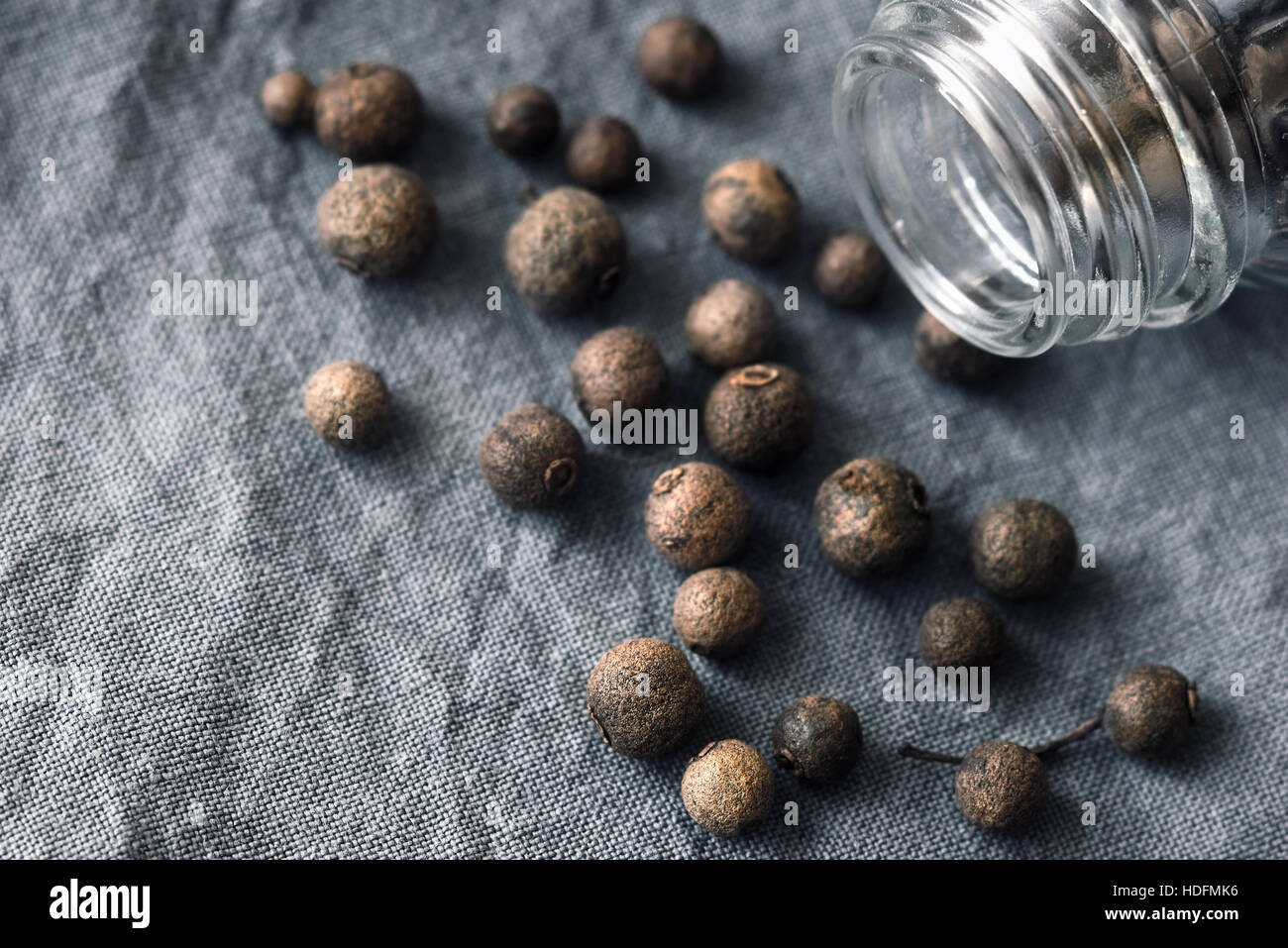 Allspice in the glass jar on the grey cloth Stock Photo