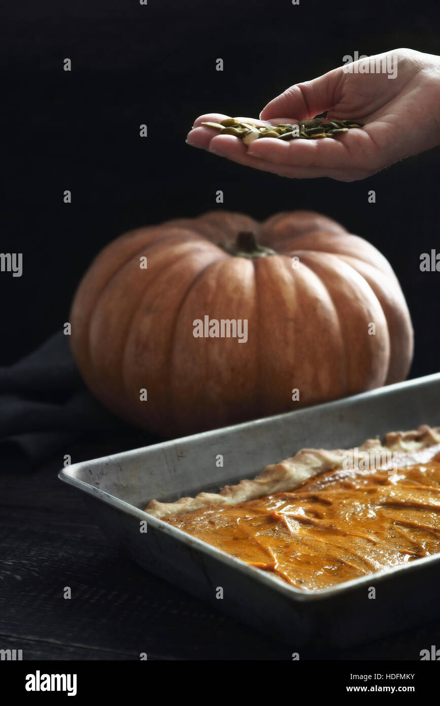 Adding pumpkin seeds in the pumpkin pie Stock Photo