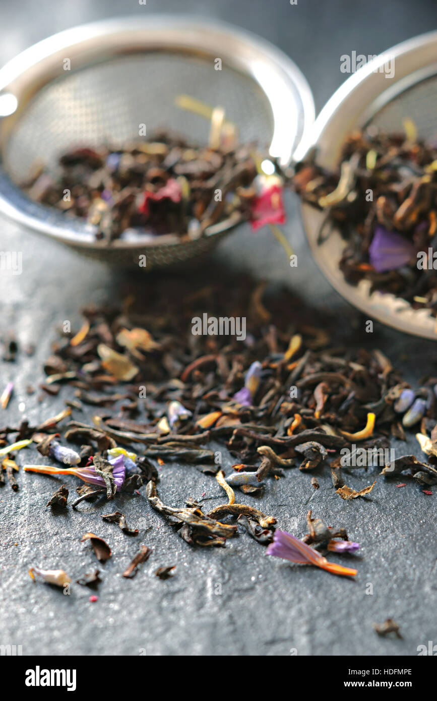 Tea with flower petal in the strainer on the stone background vertical Stock Photo