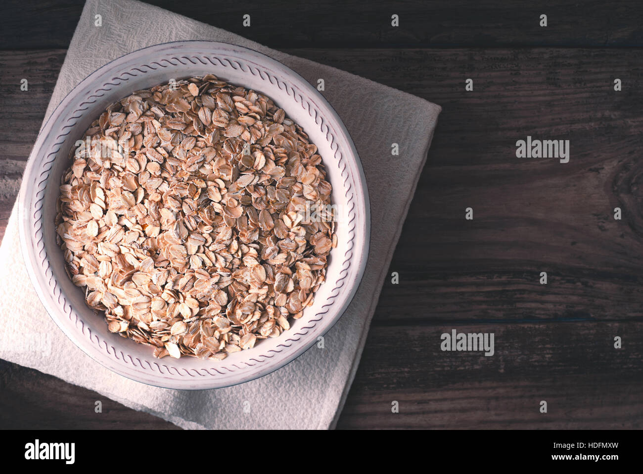 Raw oat flakes in  the bowl on the wooden table top view Stock Photo
