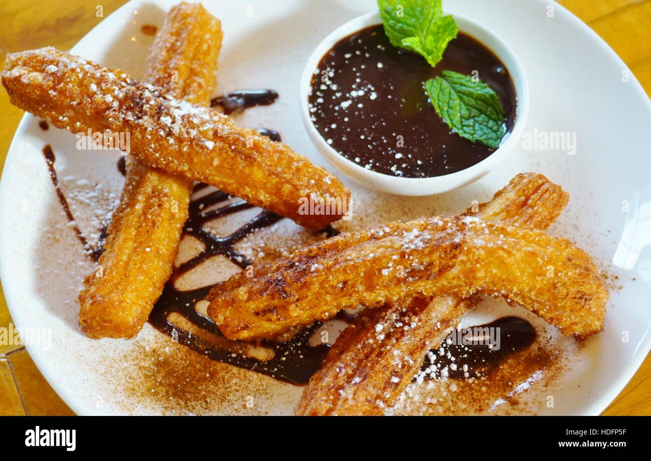 Plate of fried churro fritters with sugar and chocolate dipping sauce Stock Photo