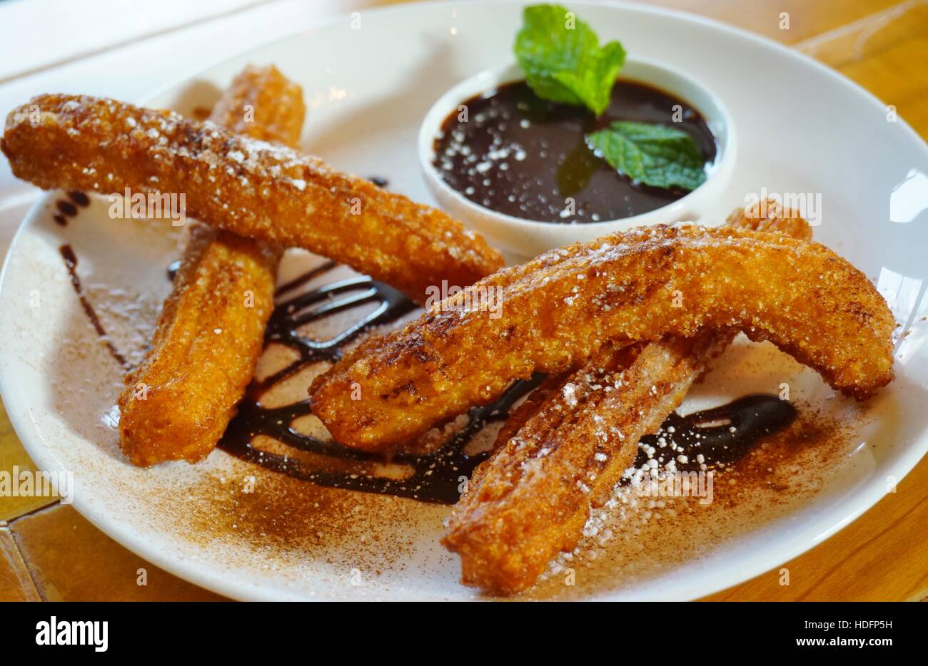 Plate of fried churro fritters with sugar and chocolate dipping sauce Stock Photo