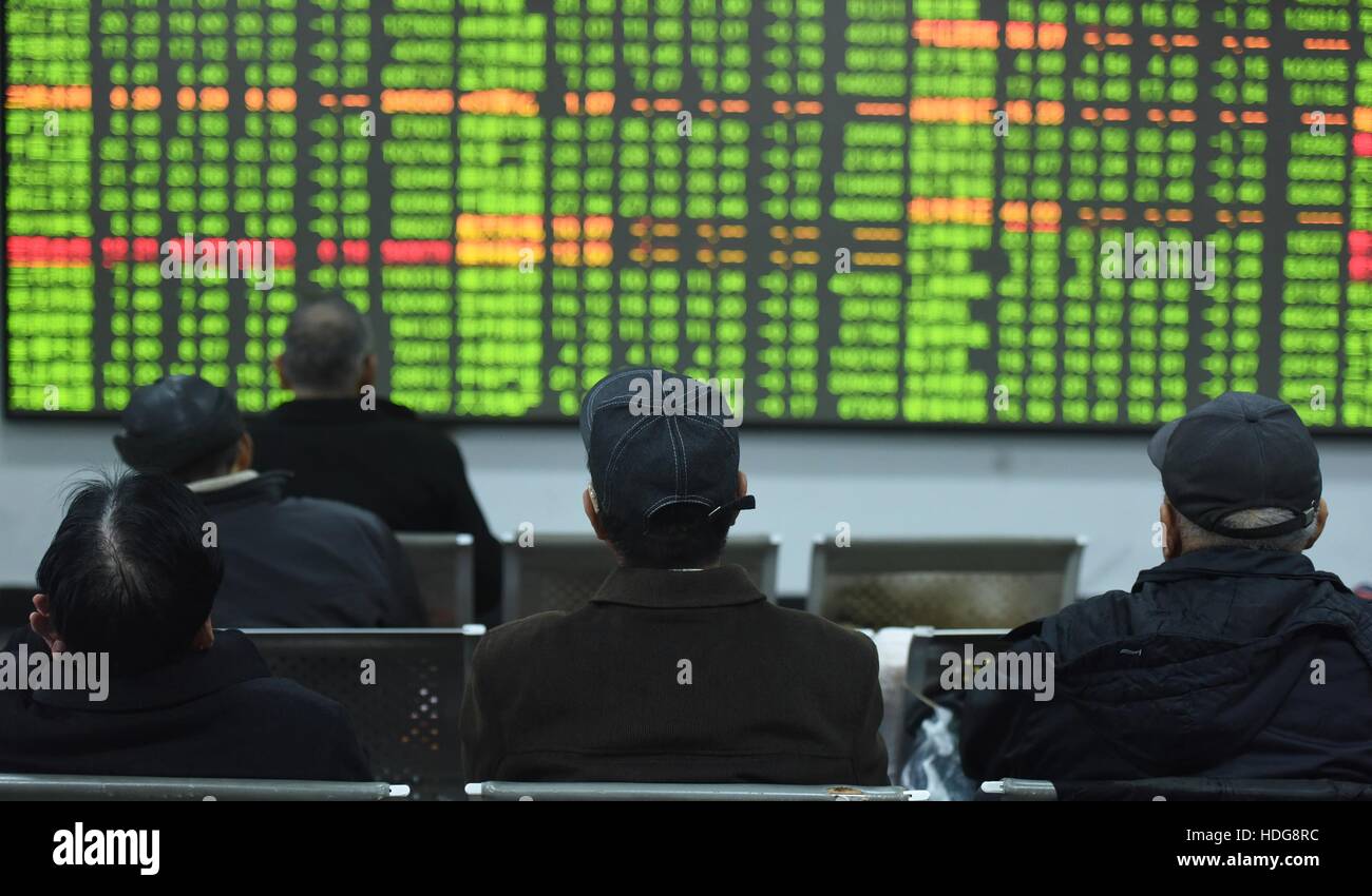 Hangzhou, China's Zhejiang Province. 12th Dec, 2016. Shareholders watch a screenboard at a stock market in Hangzhou, capital of east China's Zhejiang Province, Dec. 12, 2016. Chinese stocks tumbled on Monday as China's top insurance regulator continued to check the 'barbaric' behavior of insurers to control financial risks brought about by speculative stake buyouts. The benchmark Shanghai Composite Index dropped 2.47 percent to close at 3,152.97 points. © Long Wei/Xinhua/Alamy Live News Stock Photo