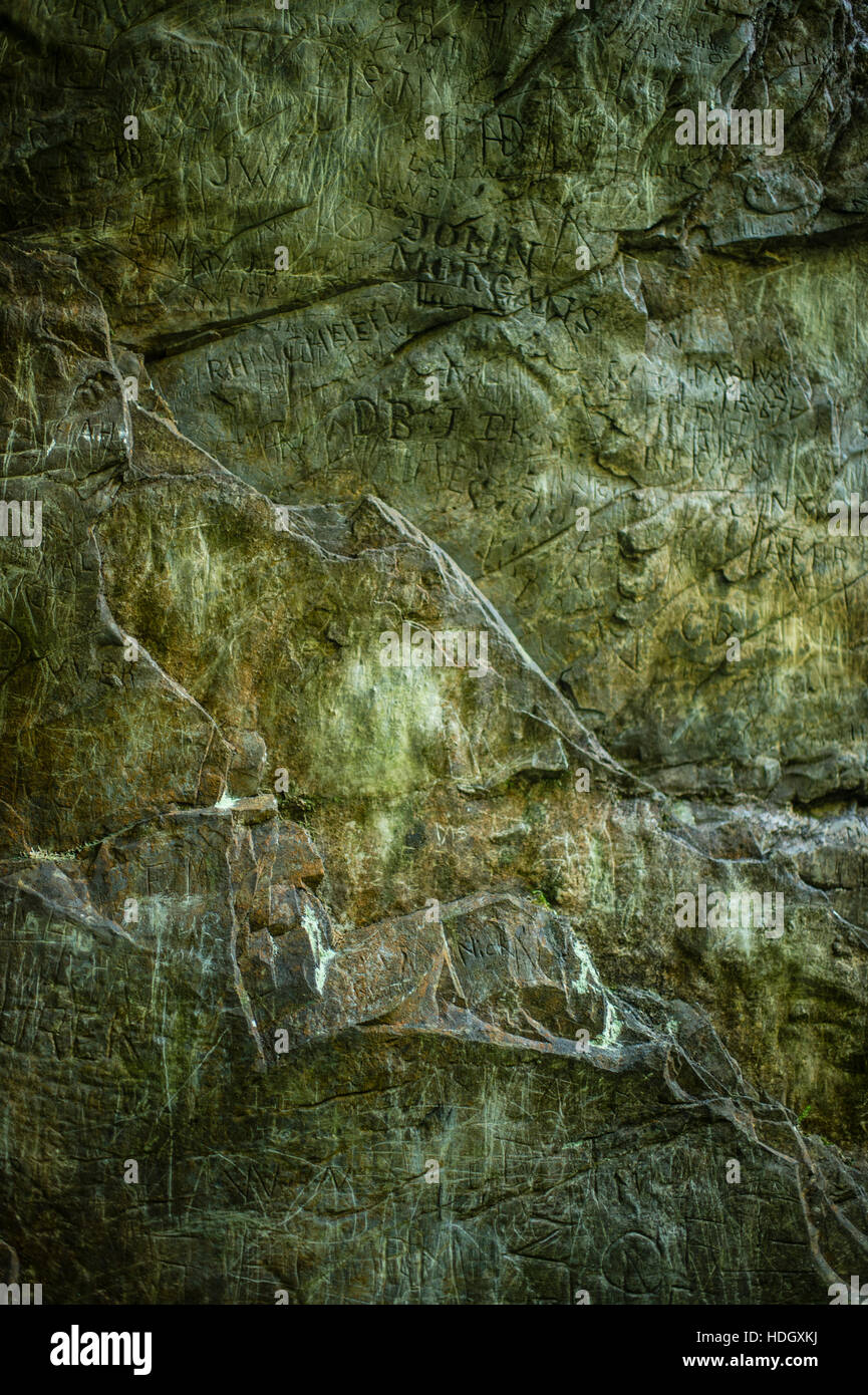 Tourism in Wales: Graffiti old names carved into the rock wall at Robbers Cave, Devil's Bridge, Ceredigion, Wales UK Stock Photo