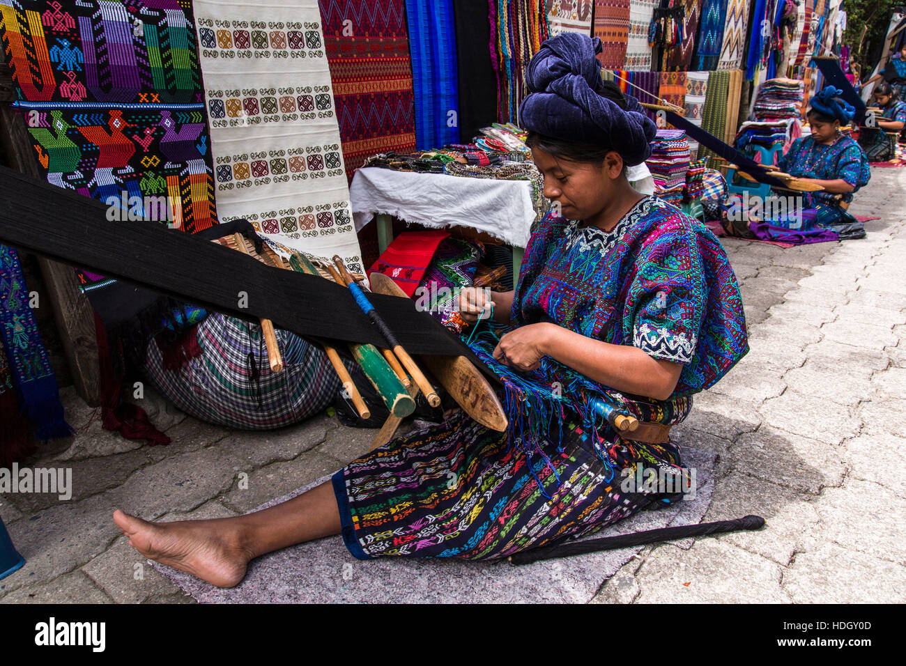 Mayan women sitting on the ground and weaving on backstrap looms in traditional dress in Santa Catarina Palopo, Guatemala. Stock Photo