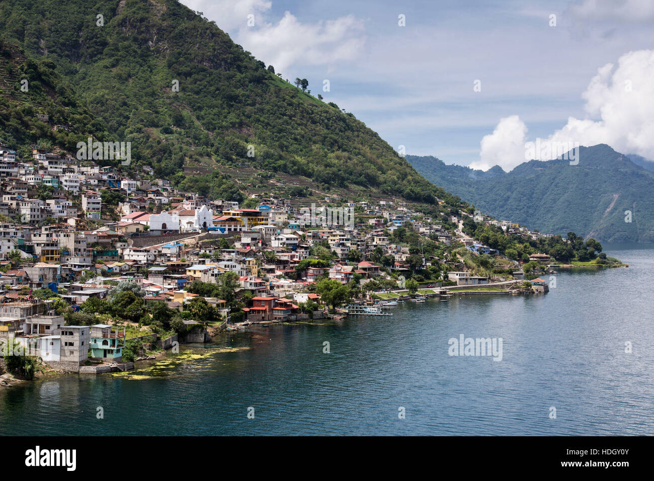 Distant view of San Antonio Palopo, Guatemala, on the shore of Lake Atitlan.  Steep hillsides drop into the lake, which is an extinict volcanic crater Stock Photo