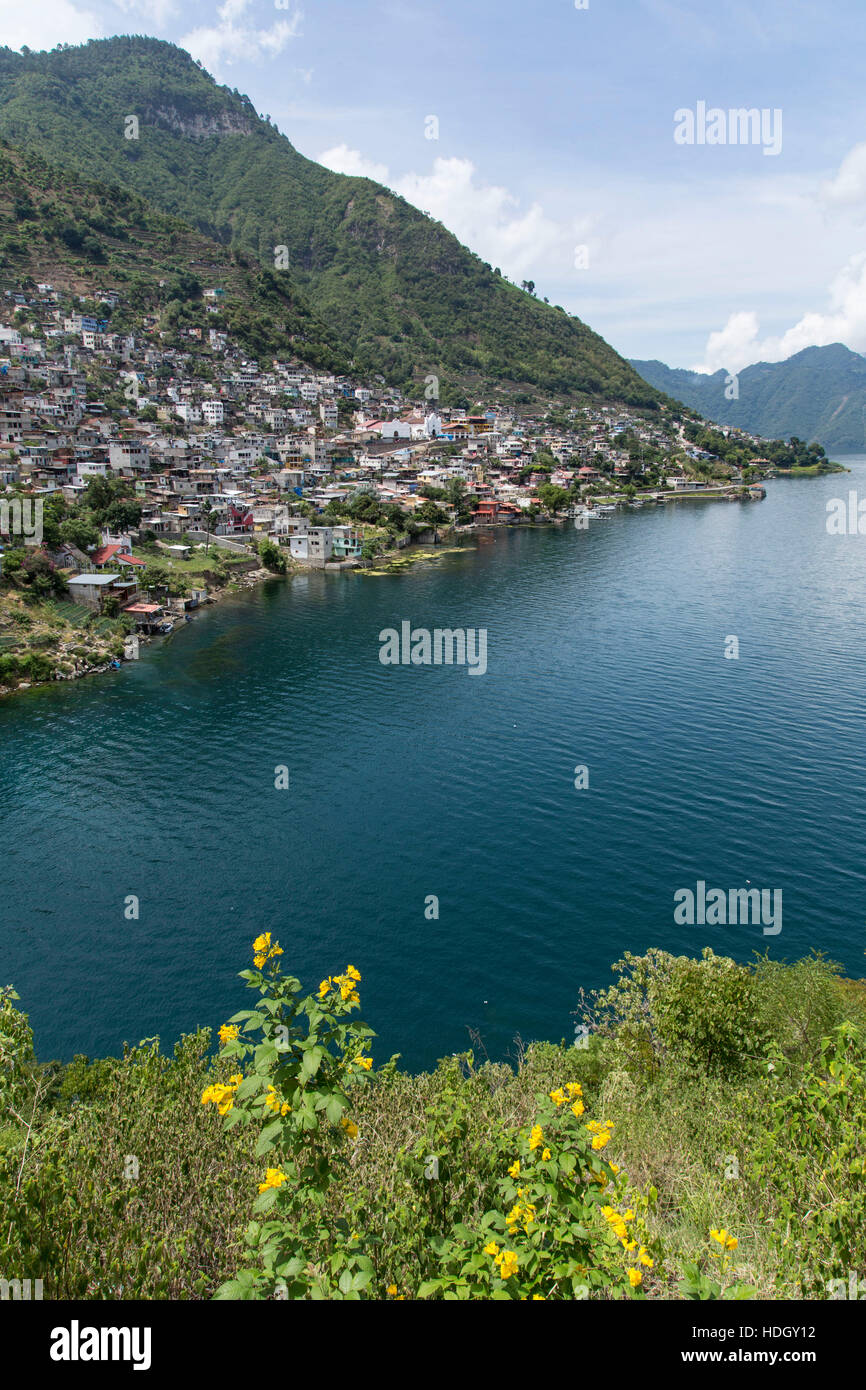 Distant view of San Antonio Palopo, Guatemala, on the shore of Lake Atitlan.  Steep hillsides drop into the lake, which is an extinict volcanic crater Stock Photo