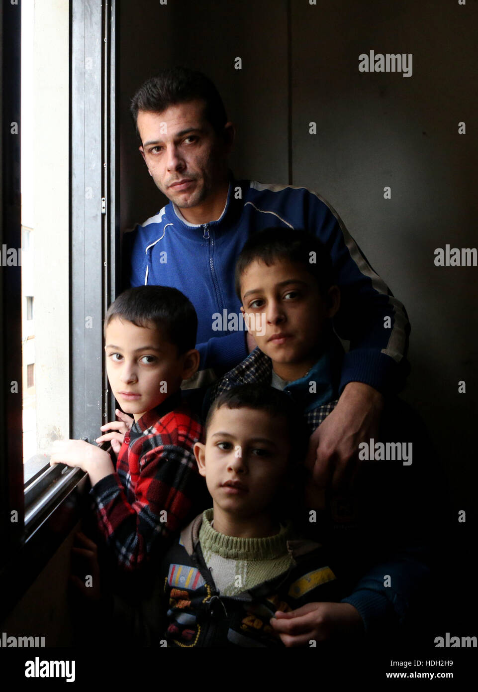 Syrian refugee Bassam Al Rahal, 30, with his sons (left to right) Omar (9), Ammar (5) and Baker (10). The family, which also includes Bassam's wife and daughter, live in an apartment in Tripoli, Lebanon, after fleeing their home in Homs, Syria. Stock Photo