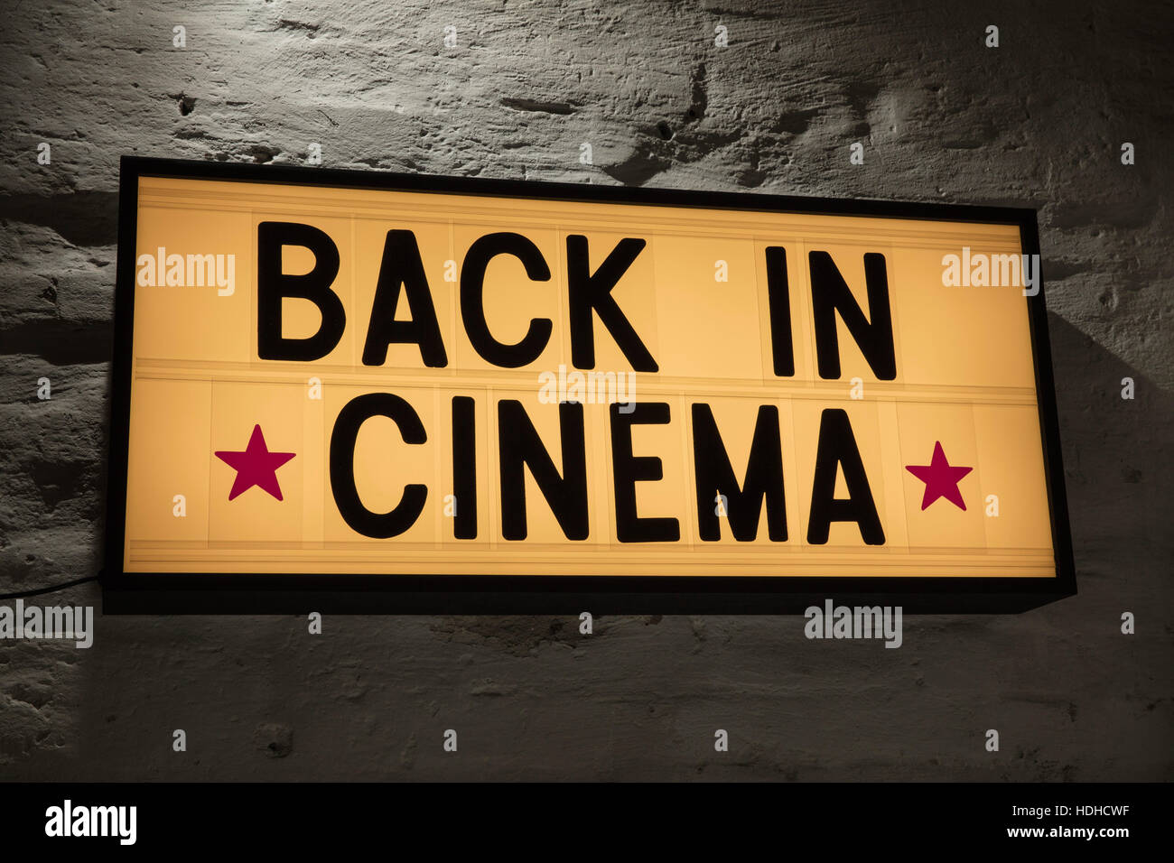 Close-up of Back In Cinema signboard against gray wall Stock Photo
