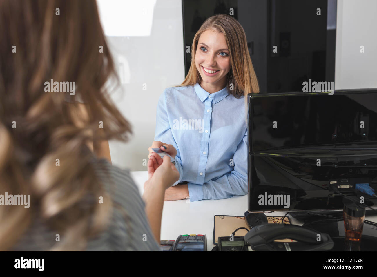 Happy saleswoman accepting payment from female customer at shoe store Stock Photo