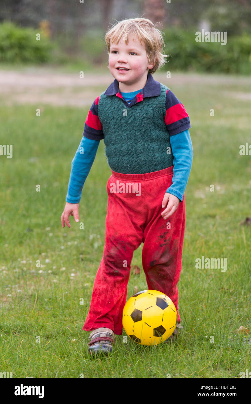 Full length of smiling boy playing soccer on field Stock Photo