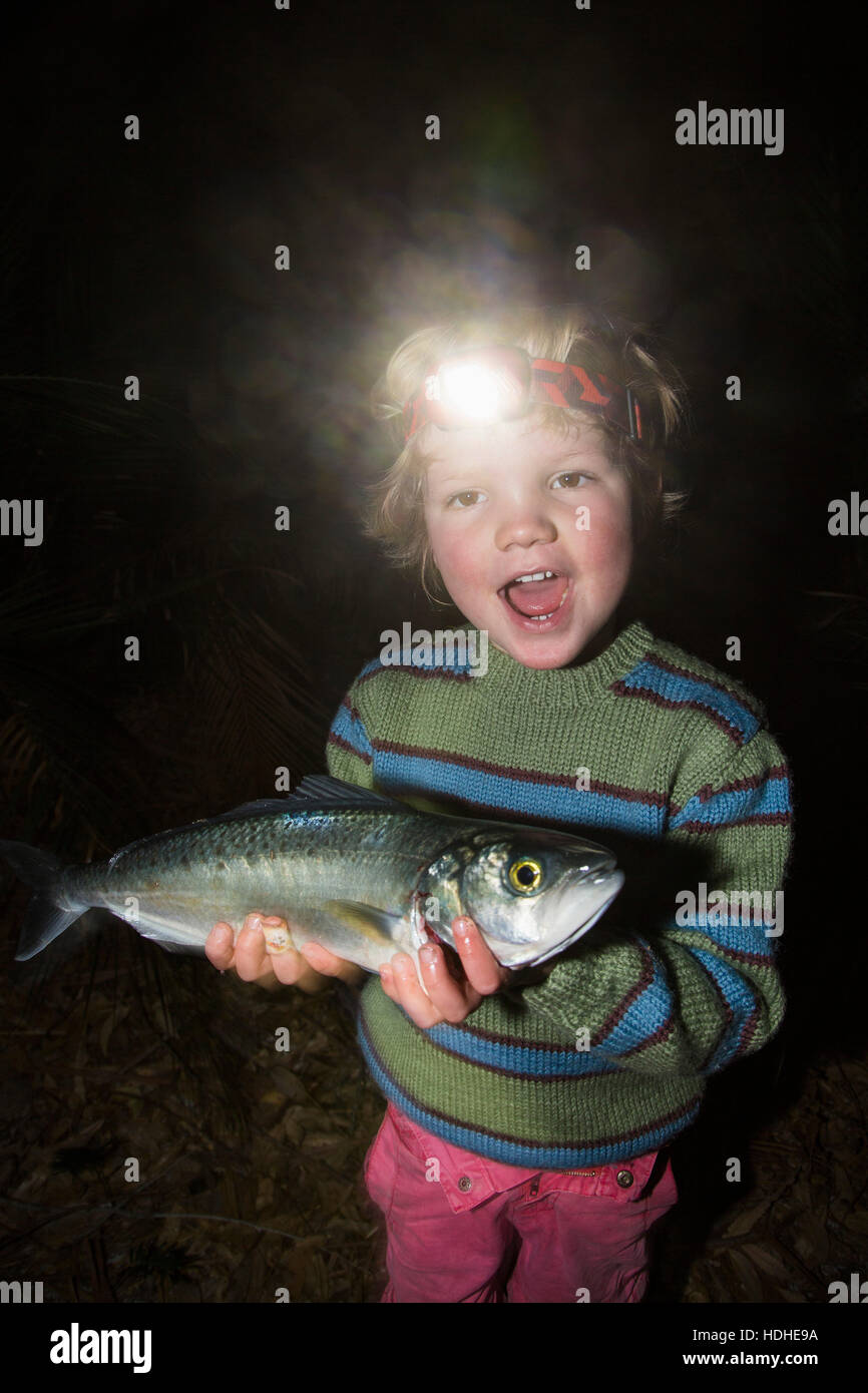 Portrait of cheerful boy wearing headlamp fish in forest Stock Photo