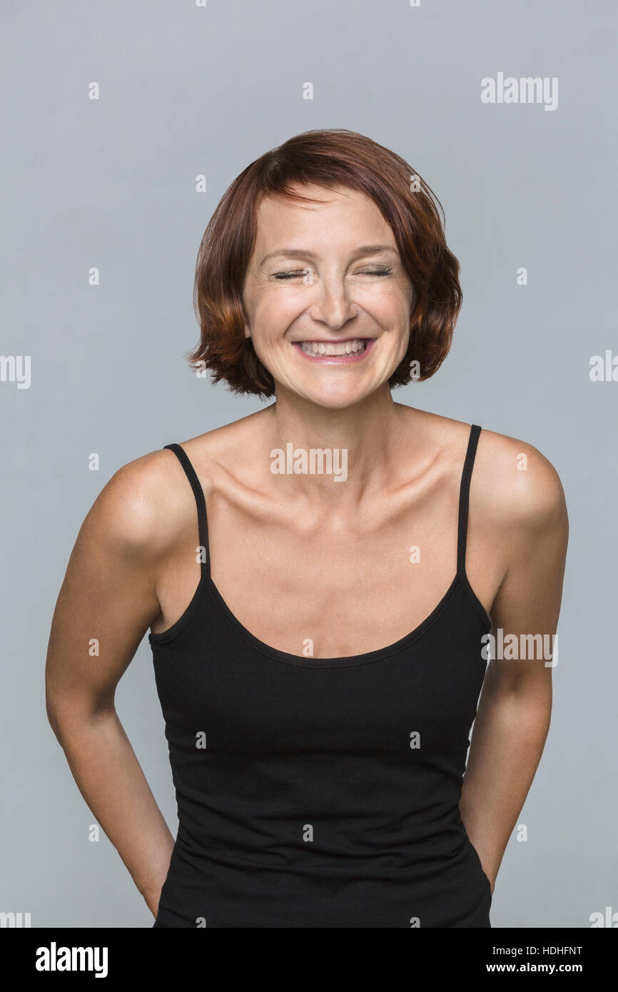 Cheerful mature woman standing against gray background Stock Photo