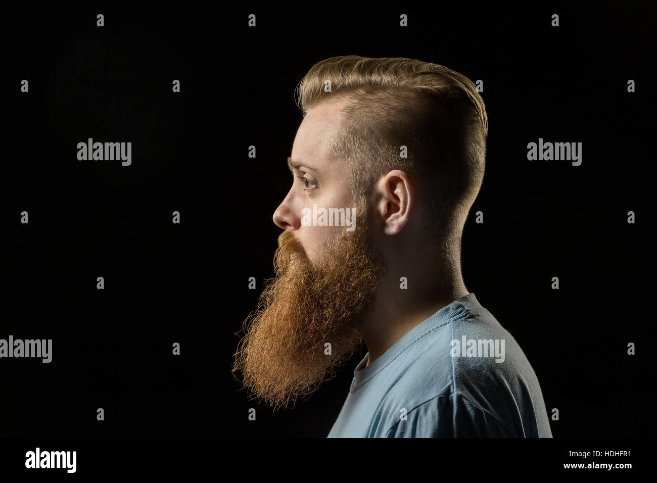 Side view of thoughtful bearded man against black background Stock Photo