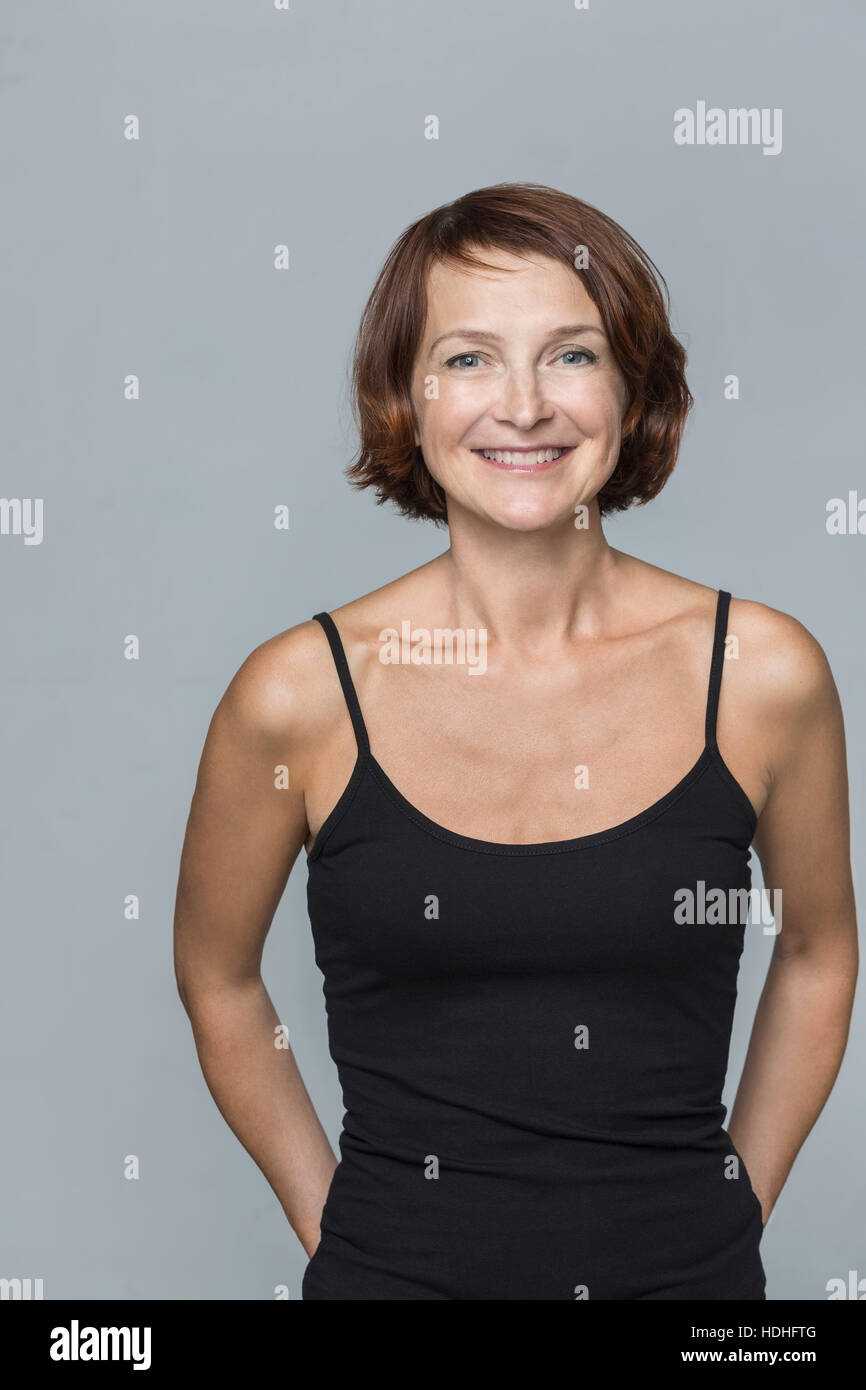 Portrait of happy mature woman standing against gray background Stock Photo