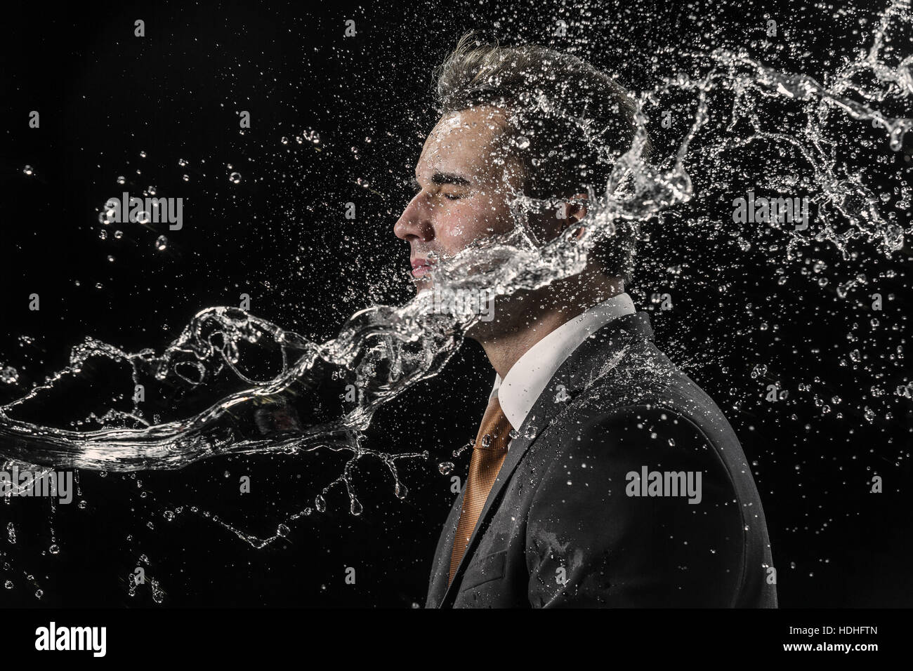 Water splashing on businessman against black background Stock Photo
