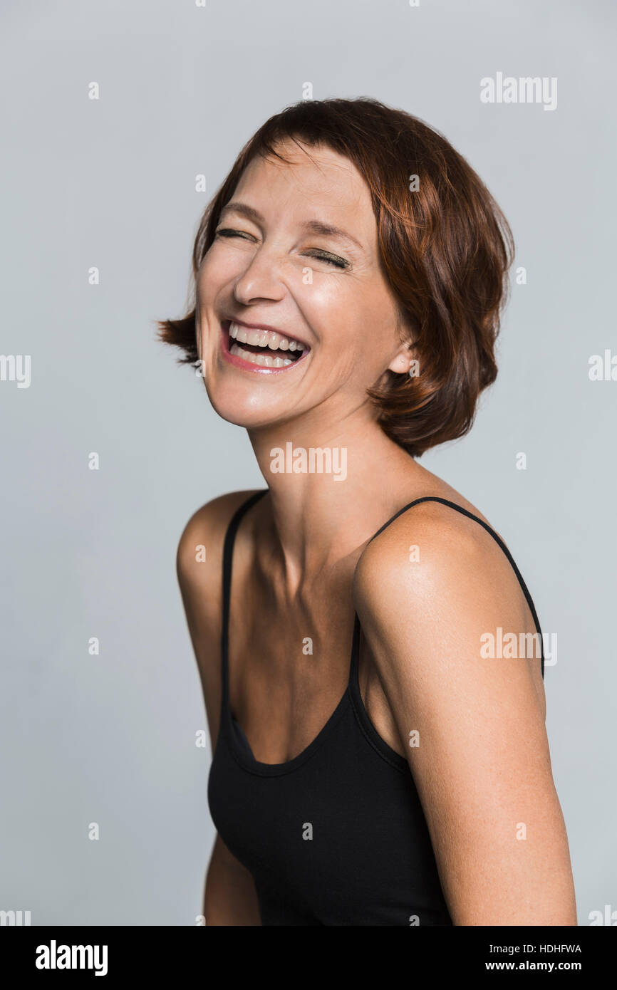 Cheerful mature woman against gray background Stock Photo