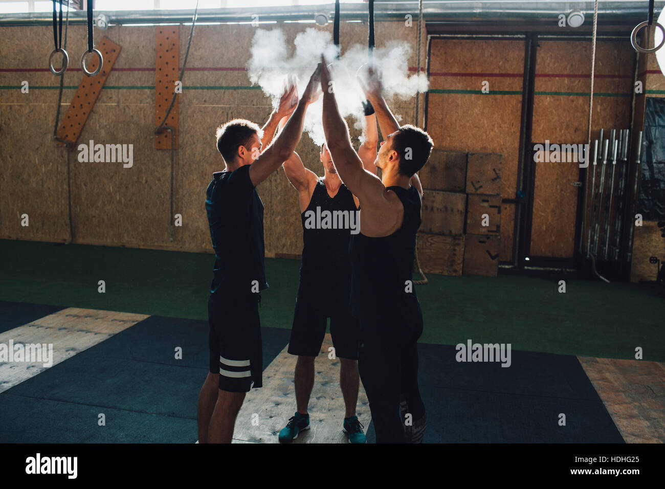 Determined sportsmen dusting sports chalk together at gym Stock Photo