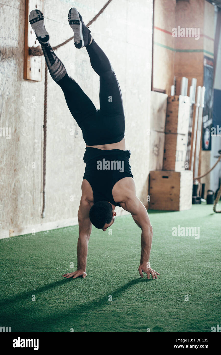 Rear view of sportsman doing handstand in gym Stock Photo