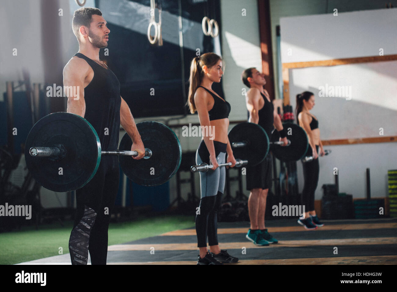 Side view of male and female athletes lifting barbells at health club Stock Photo