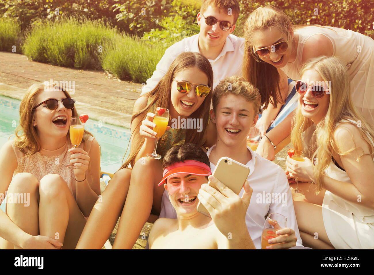 Cheerful friends taking selfie while relaxing by poolside on sunny day Stock Photo
