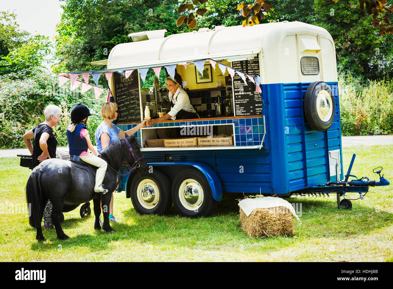 People and girl on pony queueing at a blue mobile coffee shop. Stock Photo