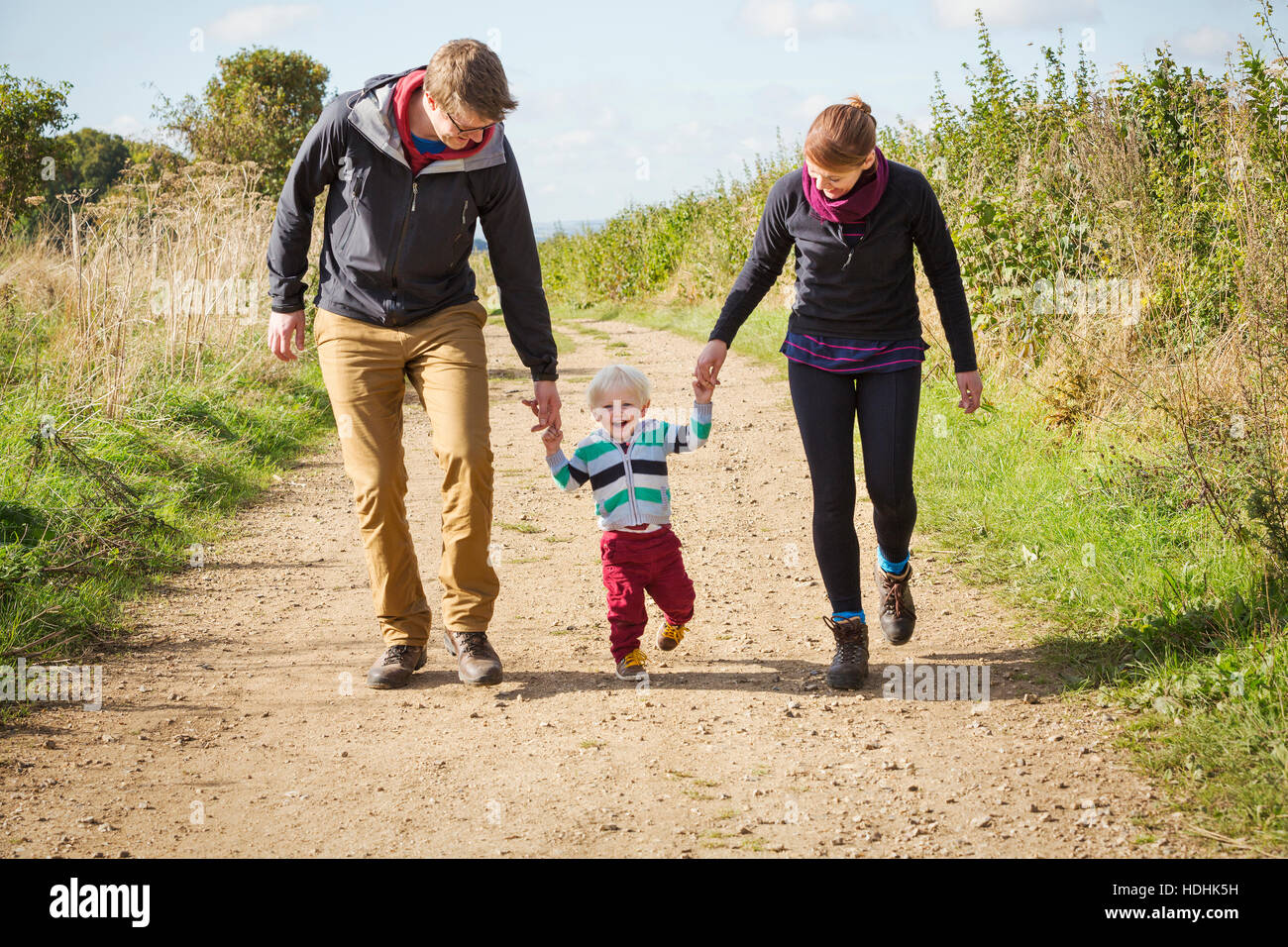 Parents and a child walking along a footpath in the countryside. Stock Photo