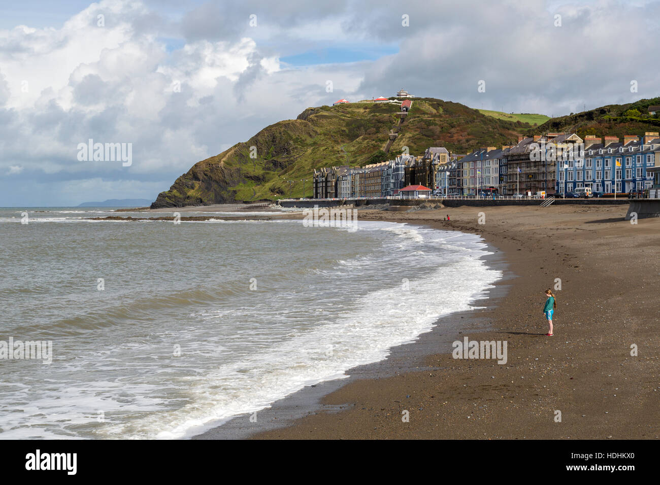 Sea front with girl standing on beach, Aberystwyth, Wales, UK Stock Photo