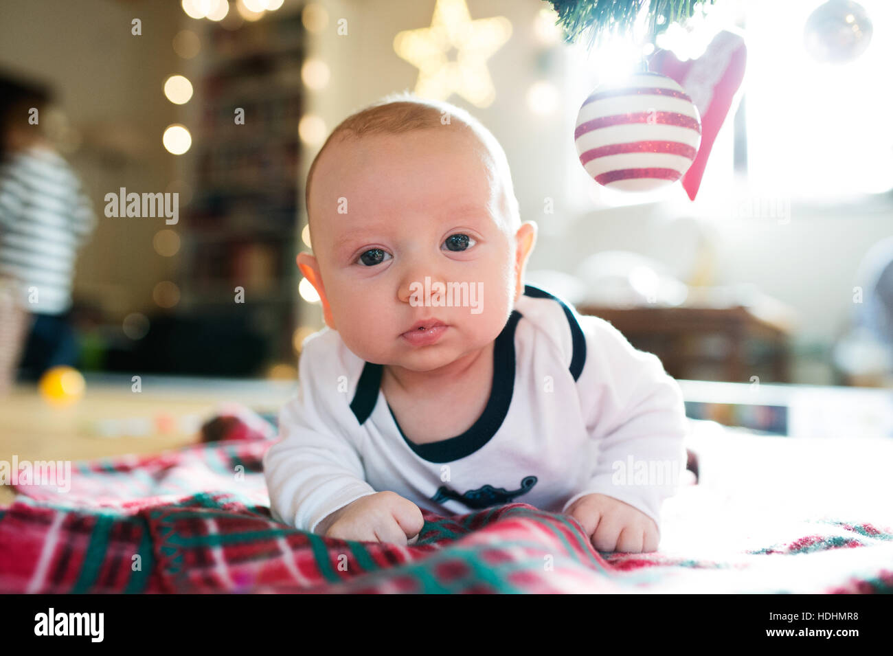 Little baby boy lying under Christmas tree on checked blanket Stock