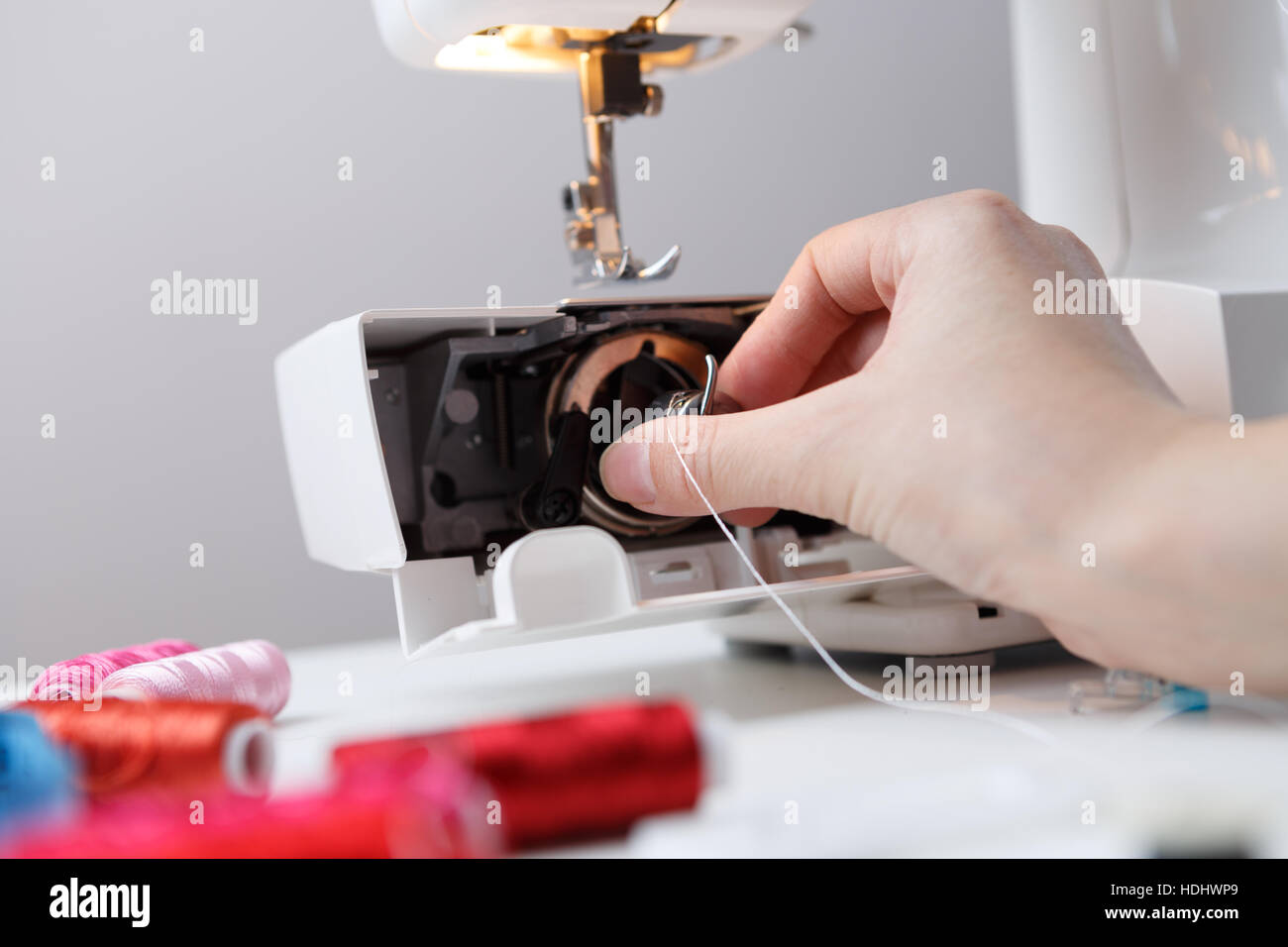 Woman inserts bobbin in sewingmachine Stock Photo Alamy
