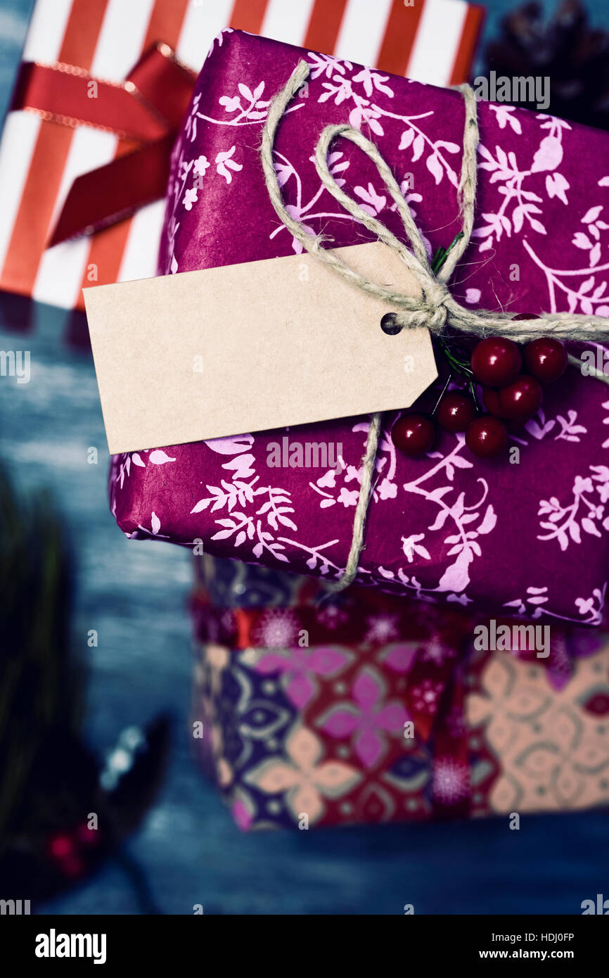 high-angle shot of some cozy christmas gifts wrapped in different nice papers and tied with ribbons and strings of different colors with a blank paper Stock Photo