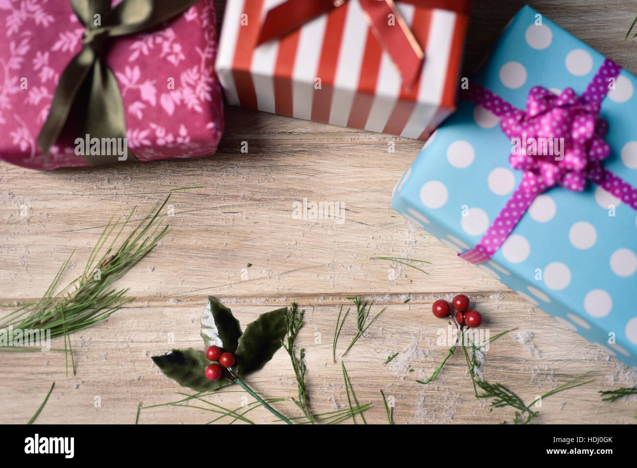 high-angle shot of some cozy gifts wrapped in different papers and tied with ribbons of different colors, and some natural ornaments, on a rustic wood Stock Photo