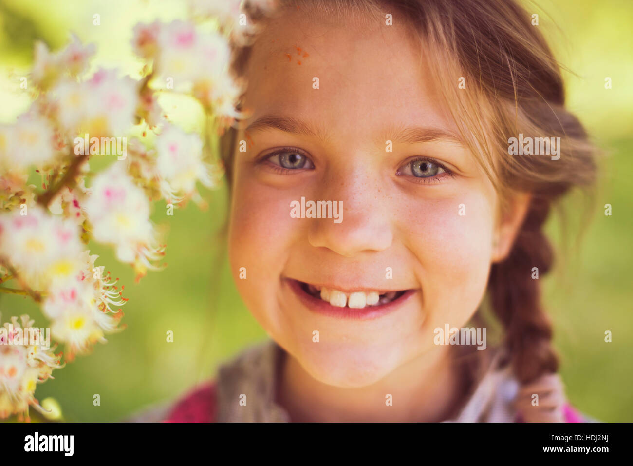 smiling child girl near blooming chestnut tree Stock Photo