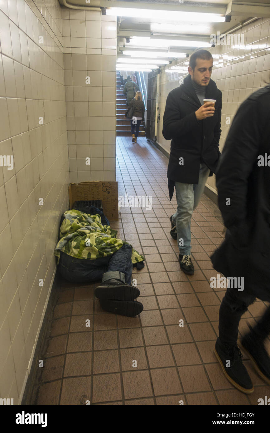 Homeless man sleeps seemingly unnoticed in a subway station entrance in midtown Manhattan, NYC. Stock Photo