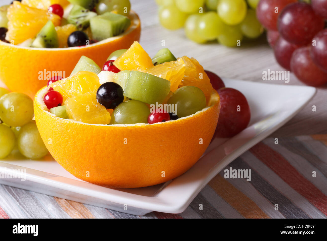 Fruit salad with grapes, currants, pears, kiwi in hollowed-out oranges closeup horizontal Stock Photo